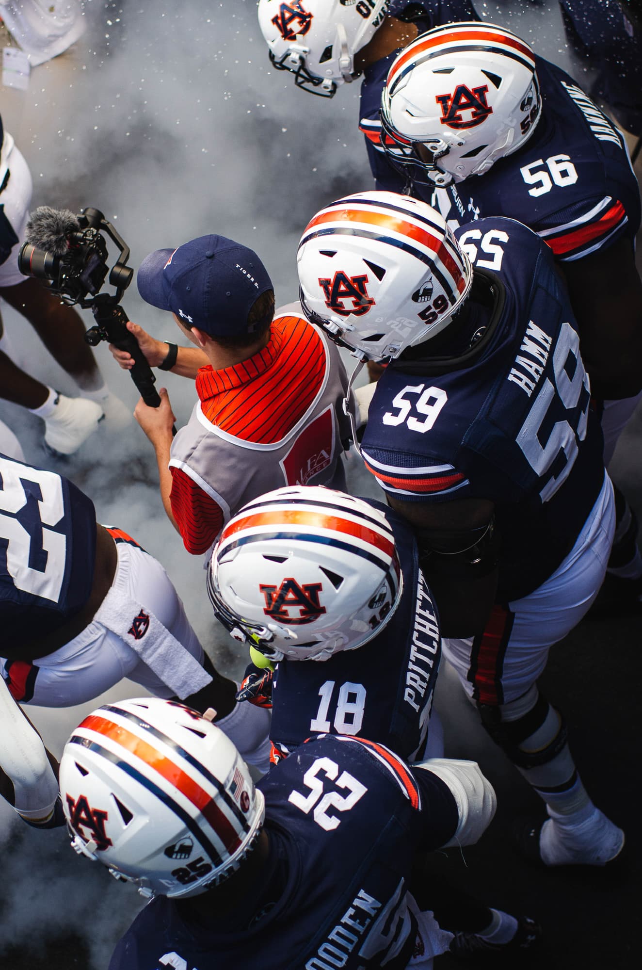 Overhead view of Luke Heslep filming Auburn football players in a smoke-filled tunnel walkout