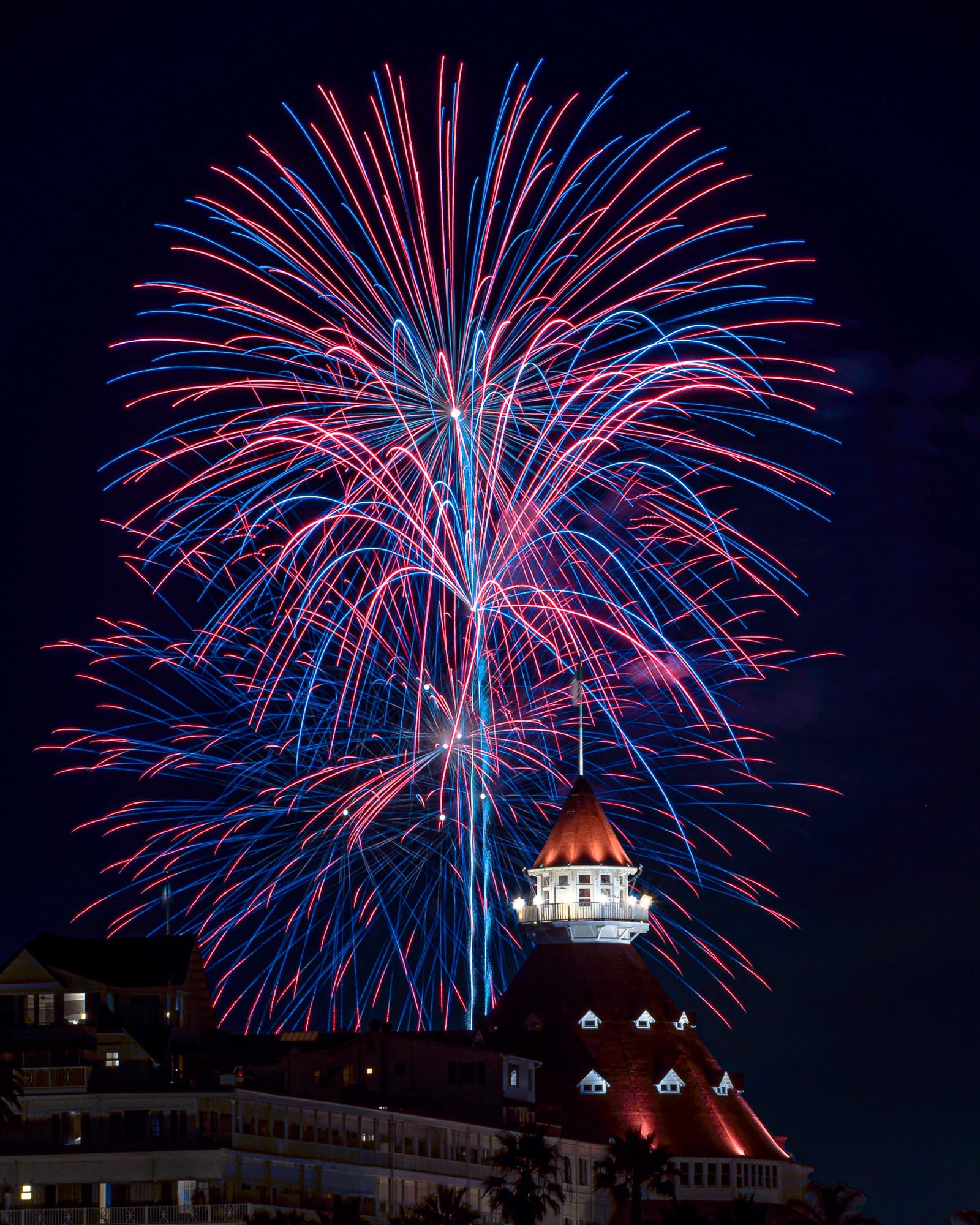 Fireworks bursting above a beachfront hotel turret