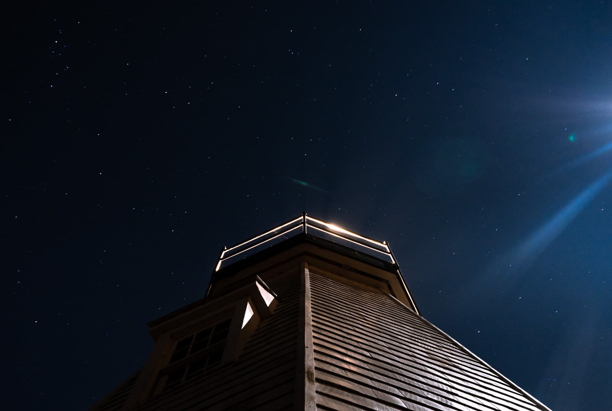 The roofline and lantern rail of a lighthouse under stars