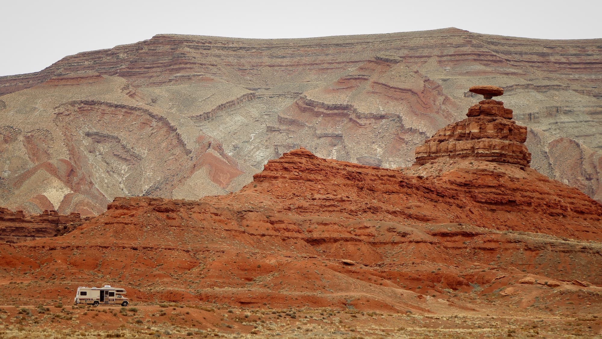 Desert mesas and a balanced rock ridge under an overcast sky