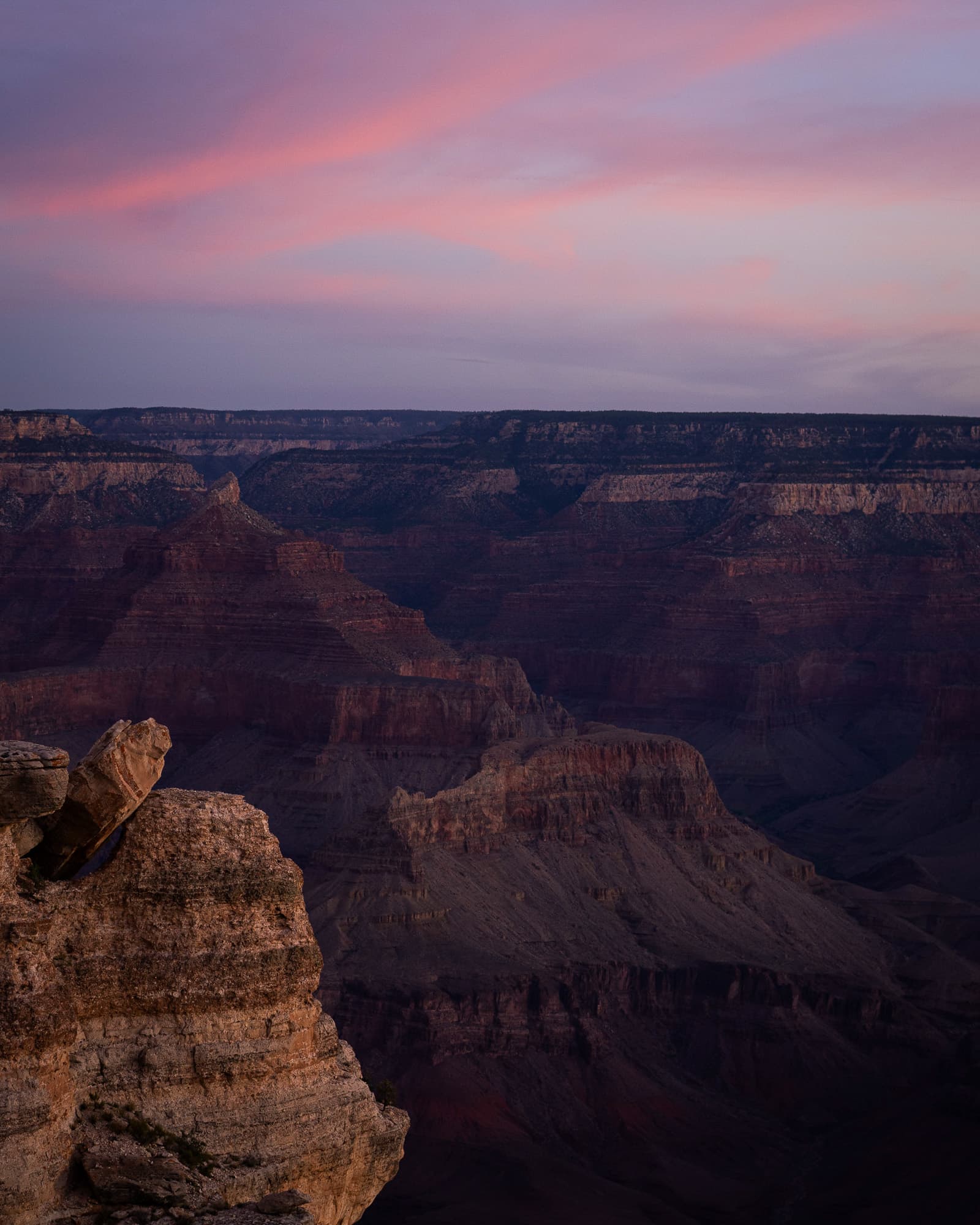 A layered canyon at twilight beneath streaked pink cloud