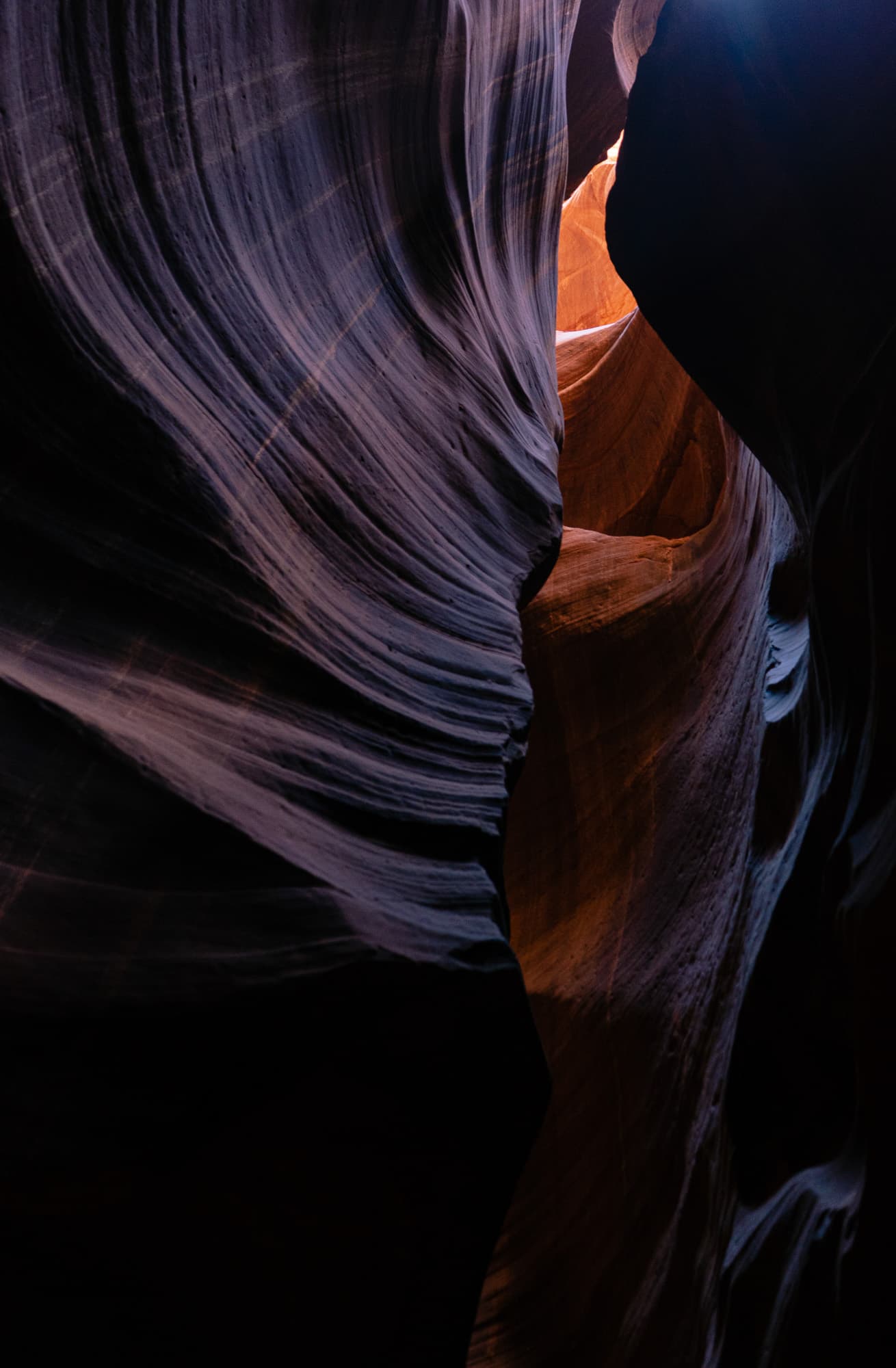 Slot canyon interior with deep shadow on one wall and warm light on the other
