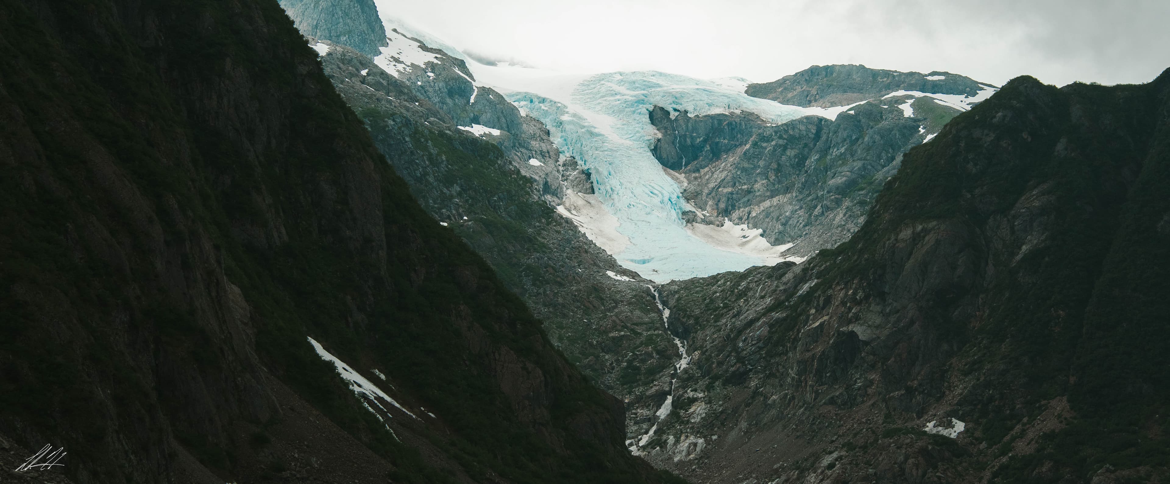 Blue glacier flowing down a mountain valley