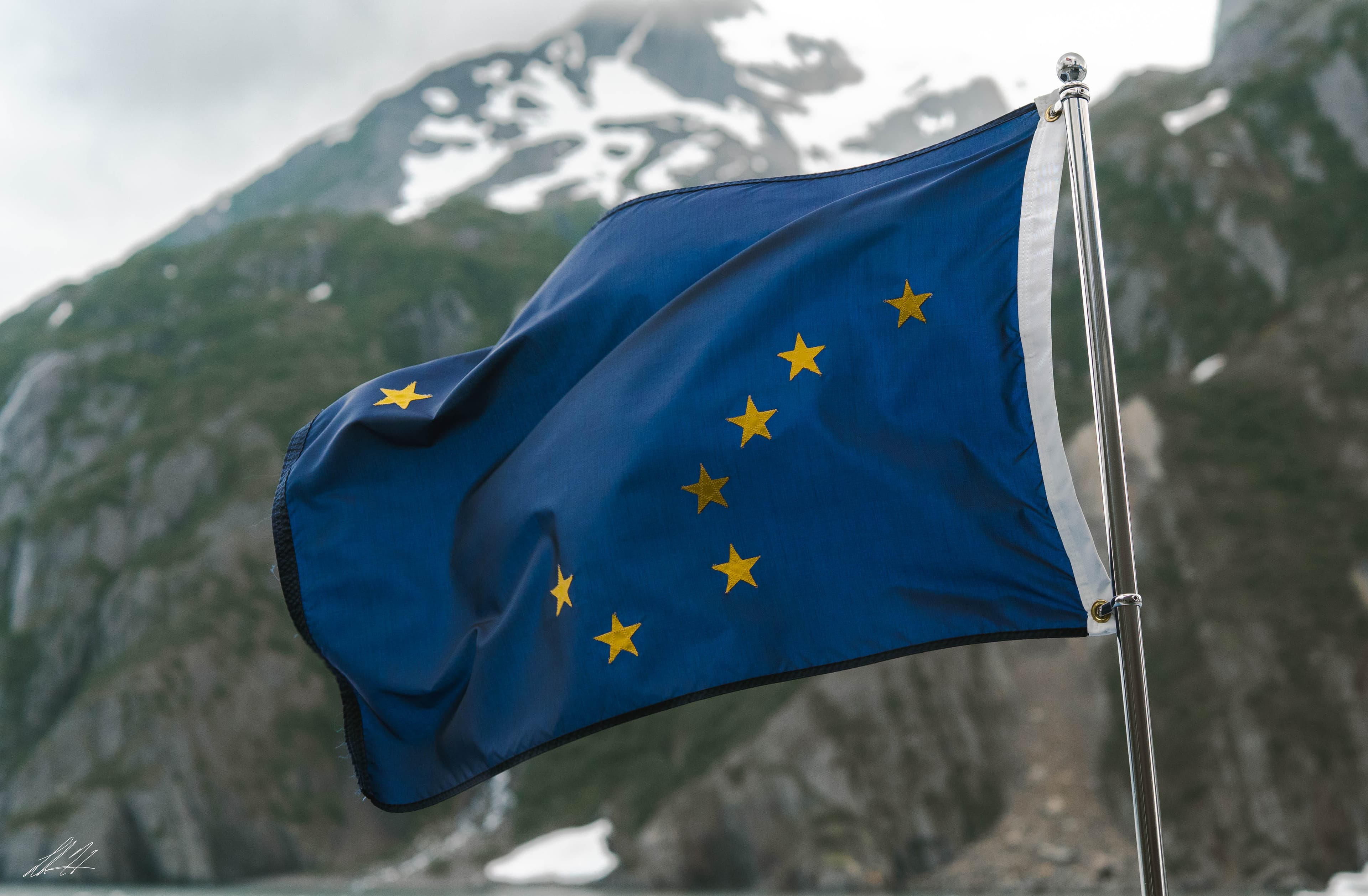 Alaska state flag against a soft mountain backdrop