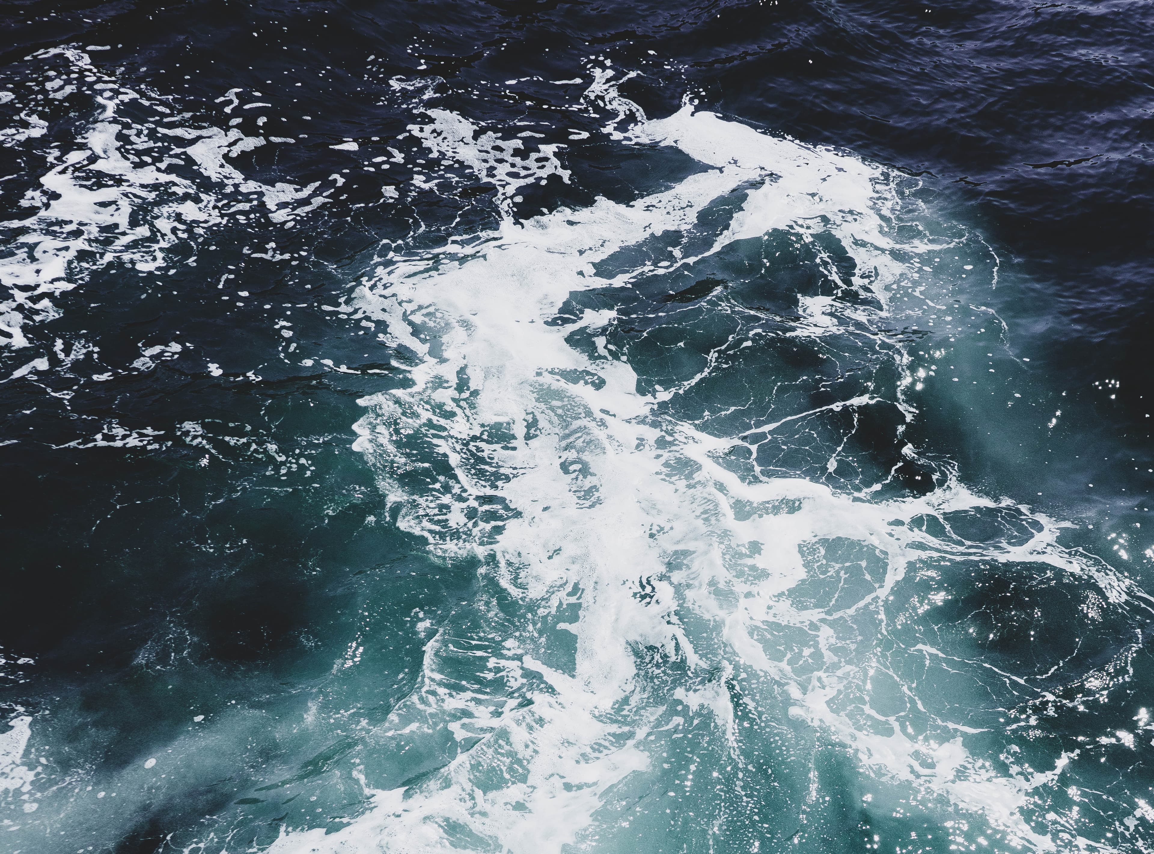 Boat wake churning through dark seawater