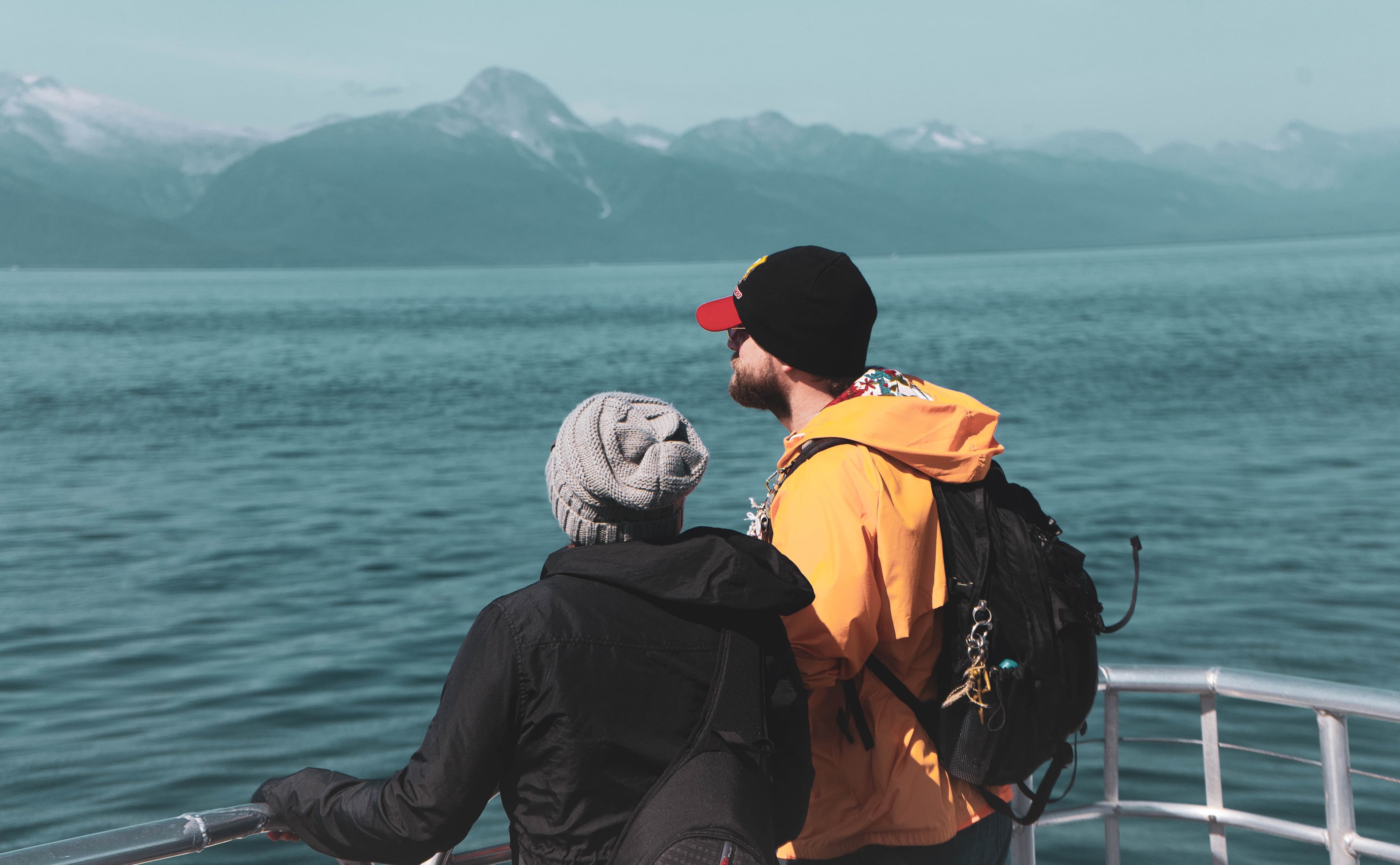 Two people looking out over water toward distant mountains