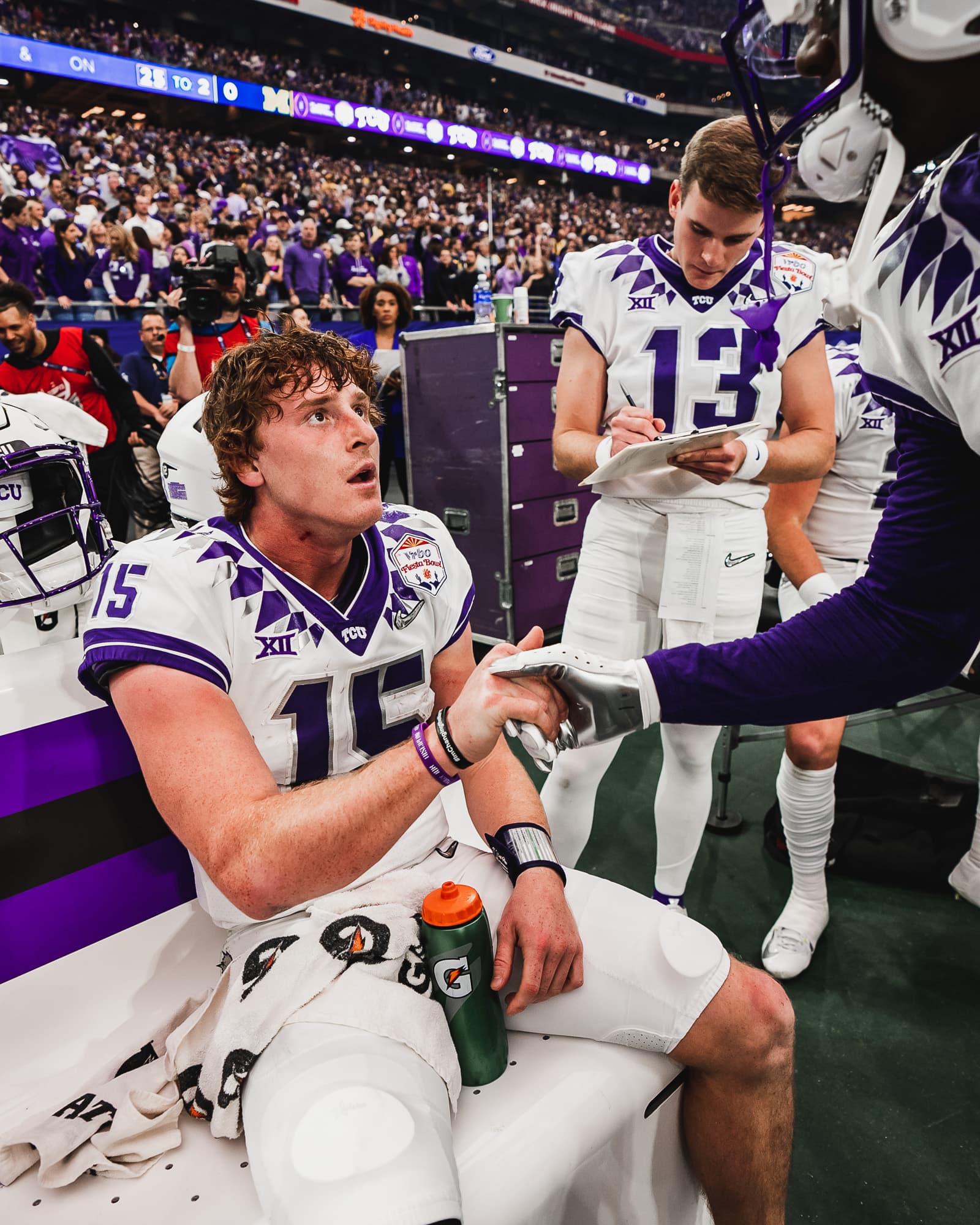 TCU player number 15 seated on the sideline shaking hands