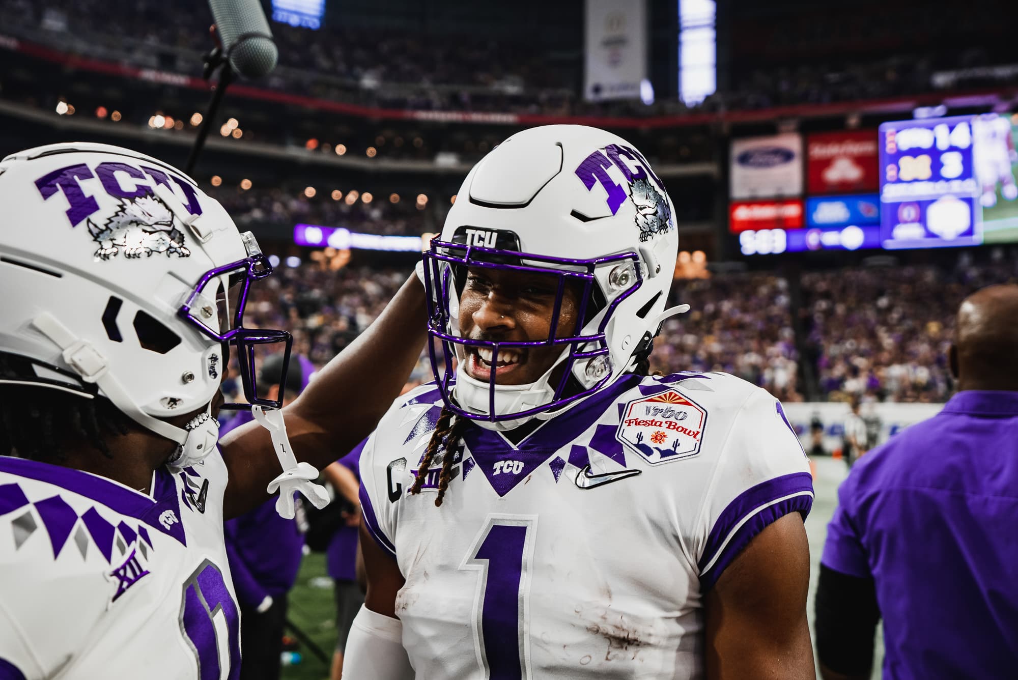 TCU player number 1 celebrating with a teammate at his helmet