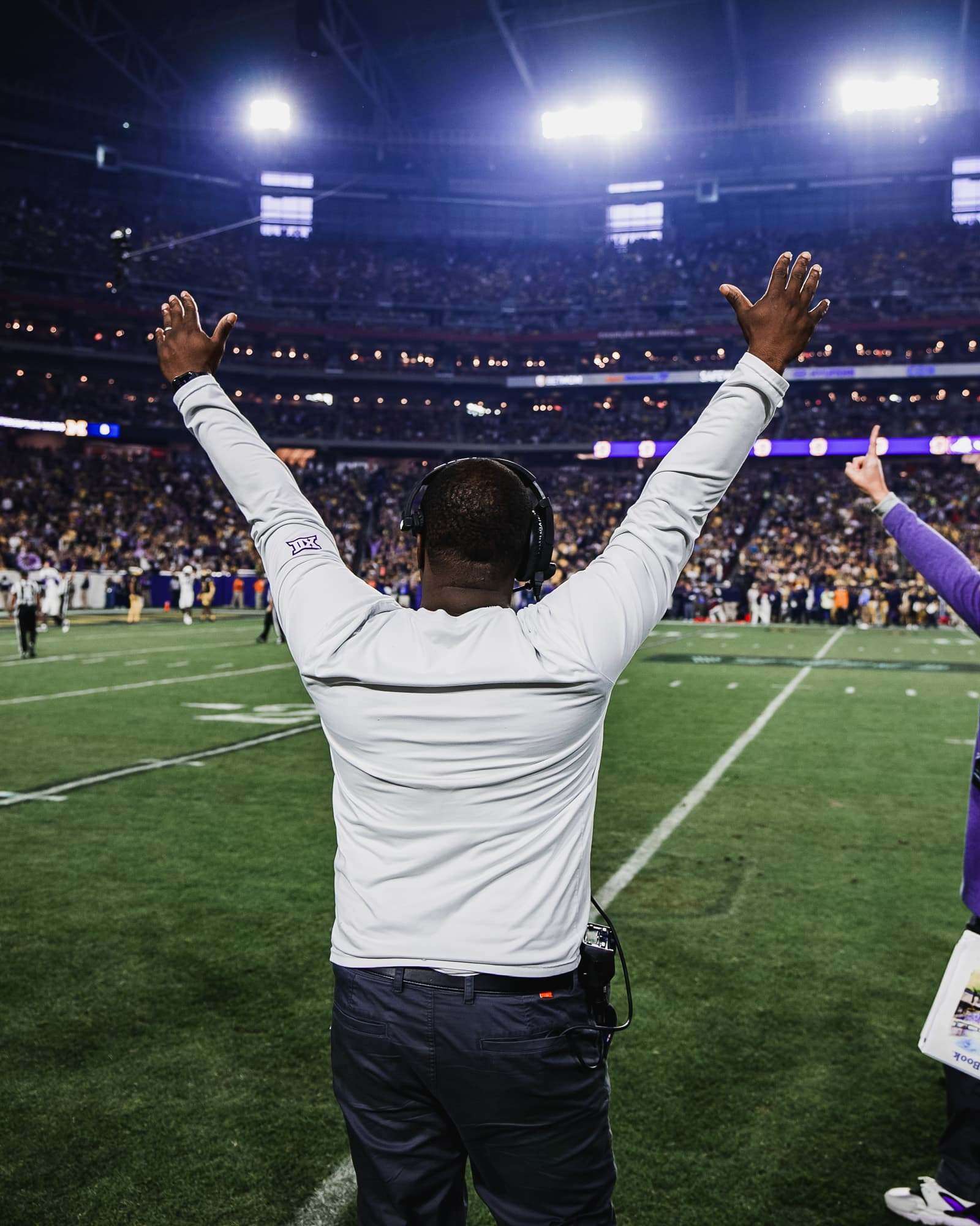 Coach with arms raised celebrating in the stadium