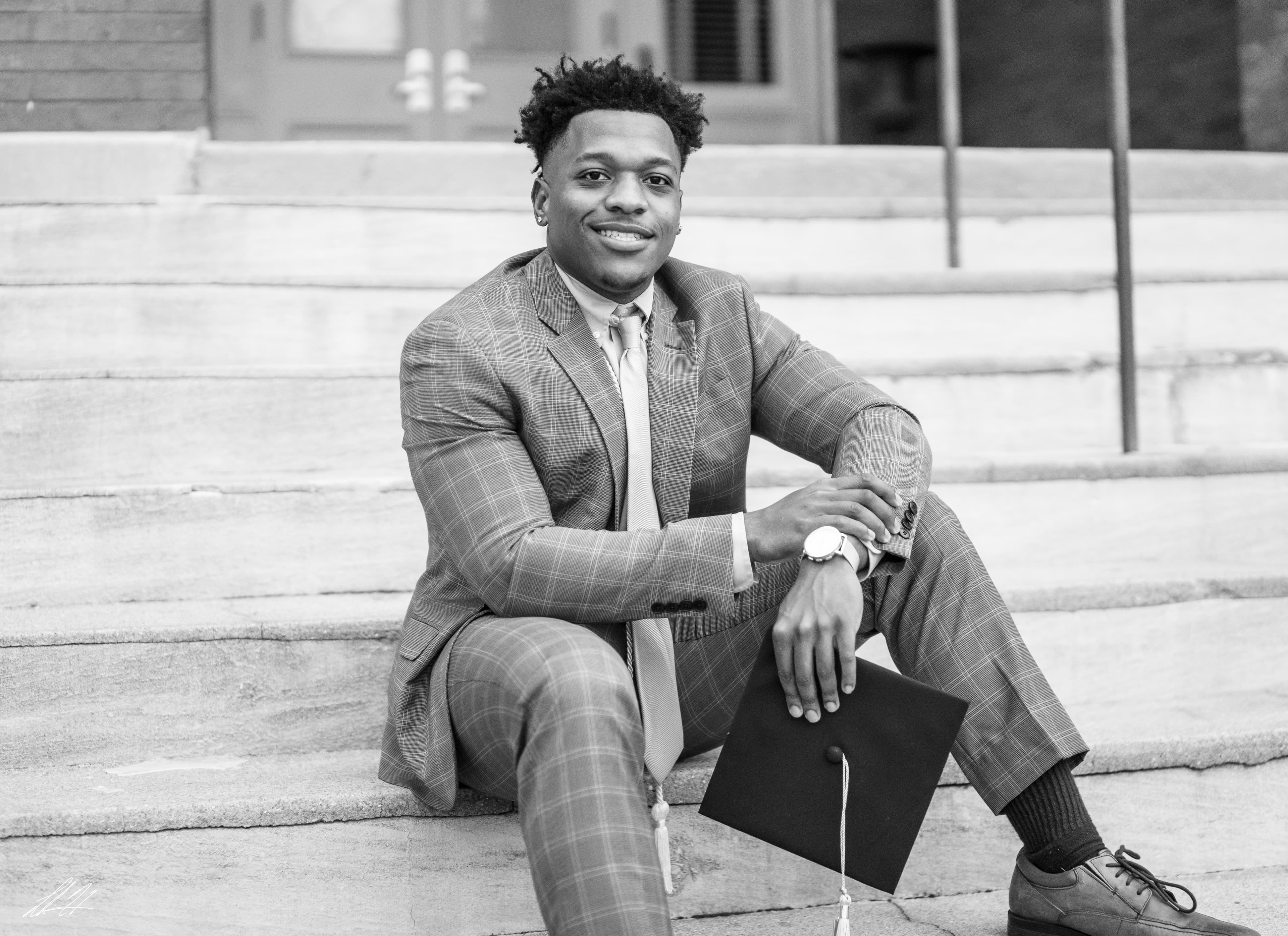 Black and white portrait of a graduate seated on stone steps