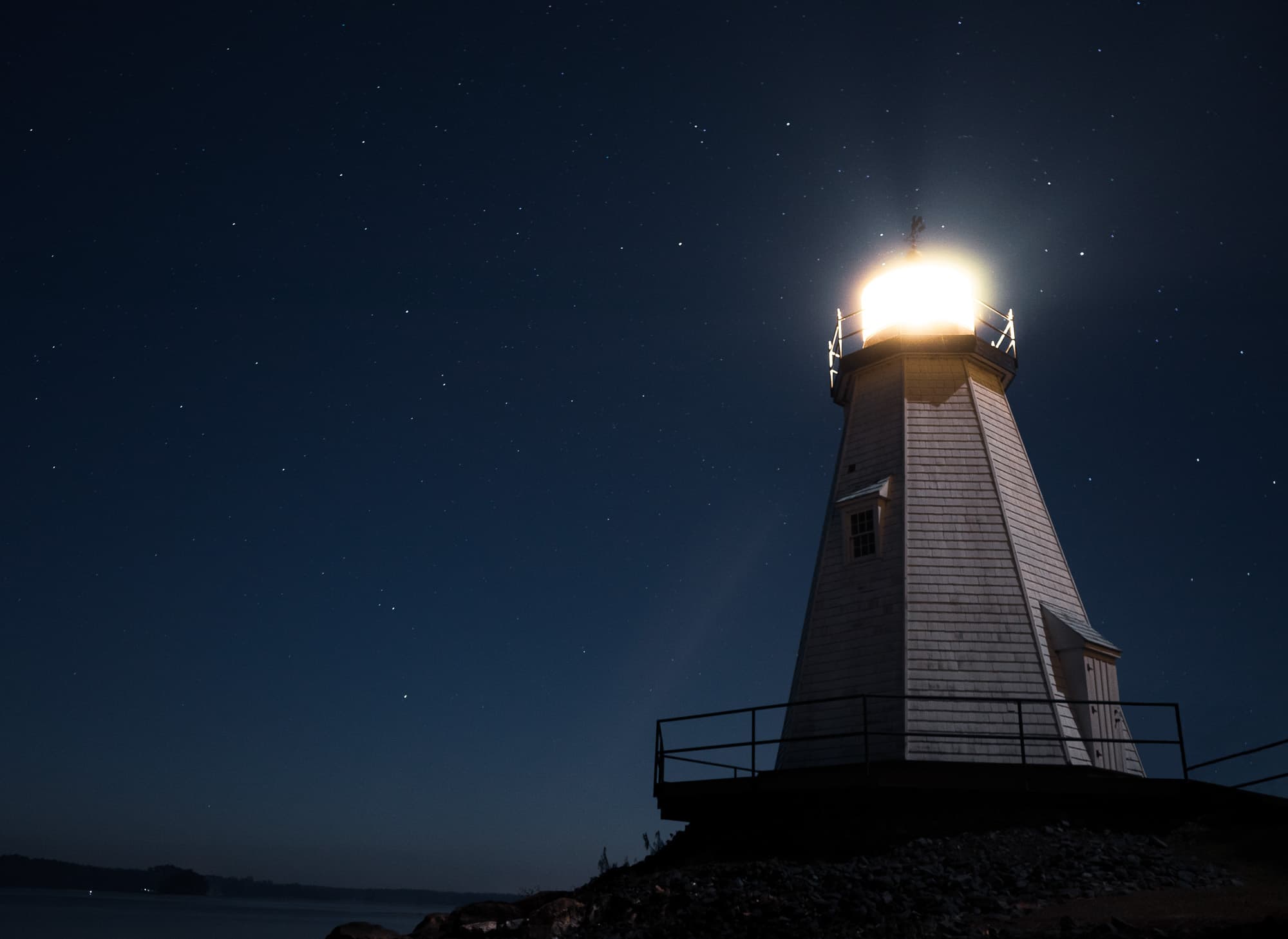 A lighthouse burning bright above the water at night